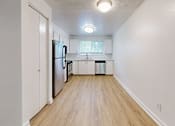Thumbnail 8 of 20 - A kitchen with a refrigerator, sink, and trash can.