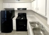 Thumbnail 12 of 12 - an empty kitchen with a sink and a stove at Cambridge Village Apartments, Houston ? 