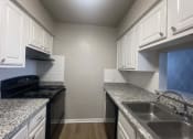 Thumbnail 15 of 17 - a kitchen with granite counter tops and white cabinets at Whispering Oaks, Texas, 77301