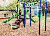 Thumbnail 19 of 20 - A playground with a green slide and a wooden platform at Ellyson Apartment Homes, Washington, 98444