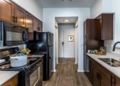 Thumbnail 9 of 9 - full kitchen with black appliances and wood flooring at theolan apartments at The Grove Germantown Apartments, Germantown, TN ?