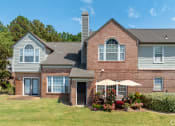 Thumbnail 6 of 9 - the front of a brick building with an umbrella on the patio at The Grove Germantown Apartments, Germantown, TN 38138 ?