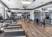 Thumbnail 2 of 9 - a gym with weights and cardio machines and a ceiling fan at The Grove Germantown Apartments, Germantown, TN 38138 ?