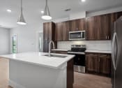 Thumbnail 30 of 35 - an empty kitchen with wooden cabinets and a white counter top at The Virginia, Seguin, Texas