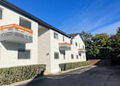 Thumbnail 3 of 13 - A white building with orange accents and a clear blue sky.