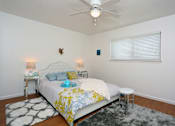 Thumbnail 5 of 13 - A bedroom with a bed, two lamps, and a rug.