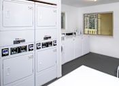 Thumbnail 10 of 13 - A row of white washing machines in a laundry room.