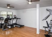 Thumbnail 9 of 13 - A gym room with a treadmill, elliptical trainer and a weight machine.