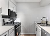 Thumbnail 25 of 30 - A kitchen with white cabinets and black appliances.