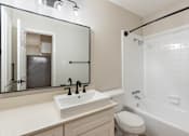 Thumbnail 18 of 30 - A white sink with a black faucet is in front of a mirror in a bathroom.