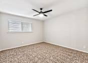 Thumbnail 23 of 30 - A room with a ceiling fan and carpeted floor.