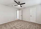 Thumbnail 27 of 30 - A room with a ceiling fan and carpeted floor.