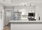 Thumbnail 6 of 30 - A modern kitchen with white cabinets and appliances.
