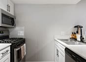 Thumbnail 30 of 30 - A modern kitchen with a black stove top and white cabinets.