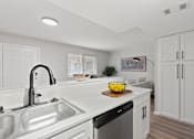 Thumbnail 7 of 30 - A modern kitchen with white cabinets and stainless steel appliances.
