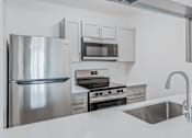 Thumbnail 22 of 42 - A modern kitchen with a stainless steel refrigerator, oven, and microwave at Water Ridge Apartments , Texas