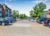 Thumbnail 41 of 42 - A parking lot with cars parked in rows and apartment buildings in the background at Water Ridge Apartments , Irving, Texas
