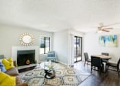 Thumbnail 20 of 42 - A living room with a fireplace, a dining table, and a rug at Water Ridge Apartments , Irving, TX