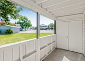 Thumbnail 33 of 42 - A white wooden balcony with a white door and a window overlooking a green lawn and a blue house at Water Ridge Apartments , Texas, 75061