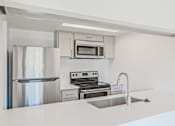 Thumbnail 23 of 42 - A modern kitchen with stainless steel appliances and white countertops at Water Ridge Apartments , Irving, TX