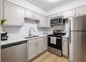 Thumbnail 7 of 35 - A kitchen with white cabinets and stainless steel appliances.