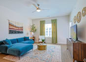 Thumbnail 19 of 52 - A living room with a blue couch and a television at The Virginia Apartments , Seguin, 78155