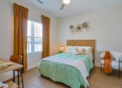 Thumbnail 21 of 52 - A bedroom with a bed, chair, and window at The Virginia Apartments , Seguin, TX