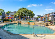 Thumbnail 17 of 42 - A large outdoor swimming pool surrounded by a fence and trees at Water Ridge Apartments , Irving, 75061