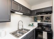 Thumbnail 12 of 35 - a kitchen with black cabinets and a stainless steel sink  at Sunset Canyon, San Antonio, 78232