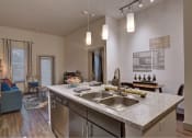 Thumbnail 2 of 22 - a kitchen with a sink and a view of a living room at The Grand at Stonecreek, San Marcos, TX
