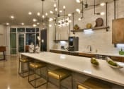 Thumbnail 10 of 22 - a kitchen with a long counter and chairs at The Grand at Stonecreek, San Marcos, TX