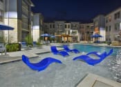 Thumbnail 16 of 22 - an outdoor pool with blue chairs and an apartment building at night at The Grand at Stonecreek, San Marcos, 78666