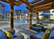 Thumbnail 19 of 22 - a swimming pool with chairs and umbrellas in front of a building at The Grand at Stonecreek, San Marcos, Texas