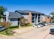 Thumbnail 34 of 55 - an apartment building with cars parked in front of it at Water Ridge Apartments, Irving