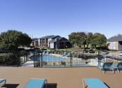 Thumbnail 22 of 55 - a pool with lounge chairs and a fence at Water Ridge Apartments, Irving, 75061