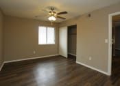Thumbnail 14 of 55 - an empty living room with a ceiling fan and a door to a closet at Water Ridge Apartments, Texas, 75061