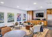 Thumbnail 9 of 42 - A modern living room with a television, a kitchen area, and a dining table at Water Ridge Apartments , Irving