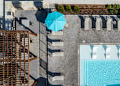Thumbnail 3 of 52 - A blue umbrella is on a patio next to a pool at The Virginia Apartments , Seguin