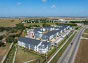 Thumbnail 52 of 52 - A large building complex with a parking lot in front at The Virginia Apartments , Seguin