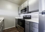 Thumbnail 6 of 42 - A kitchen with a stove, oven, microwave, and refrigerator.