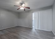 Thumbnail 12 of 42 - A room with a ceiling fan and light fixture, wooden flooring, and a window with blinds.