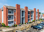Thumbnail 19 of 42 - A red brick apartment building with a parking lot in front.