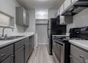Thumbnail 5 of 42 - A kitchen with a black refrigerator and stove top oven.