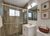 Thumbnail 14 of 23 - A bathroom with a white sink and a glass shower stall.