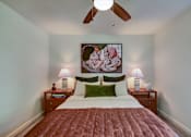 Thumbnail 10 of 23 - A bedroom with a bed, two lamps, and a painting on the wall.