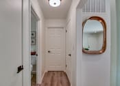 Thumbnail 12 of 23 - A hallway with a white door and a mirror on the wall.