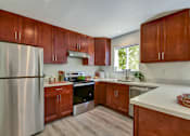 Thumbnail 7 of 23 - A kitchen with wooden cabinets and a stainless steel refrigerator.