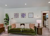 Thumbnail 22 of 23 - A living room with a green couch and a potted plant.