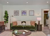 Thumbnail 4 of 23 - A living room with a green couch and a coffee table.