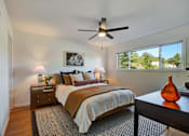 Thumbnail 13 of 39 - A bedroom with a bed, nightstand, and a ceiling fan.